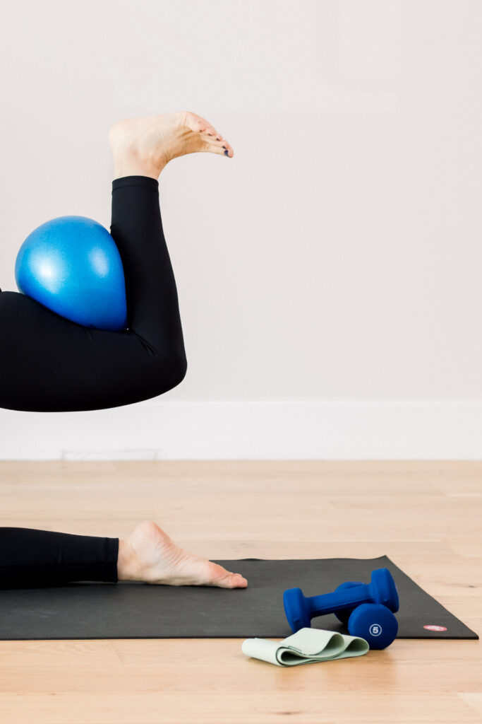 Detailed image of a pilates instructor's leg with a blue ball.