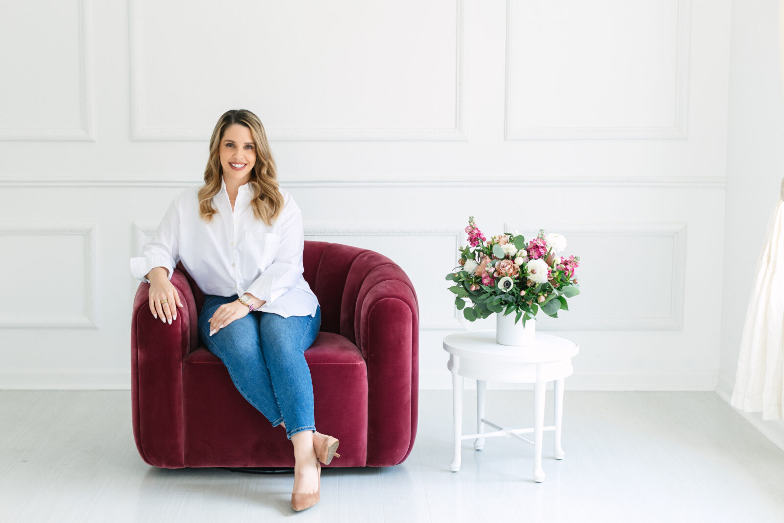 a woman sat on a rose colored, velvet chair