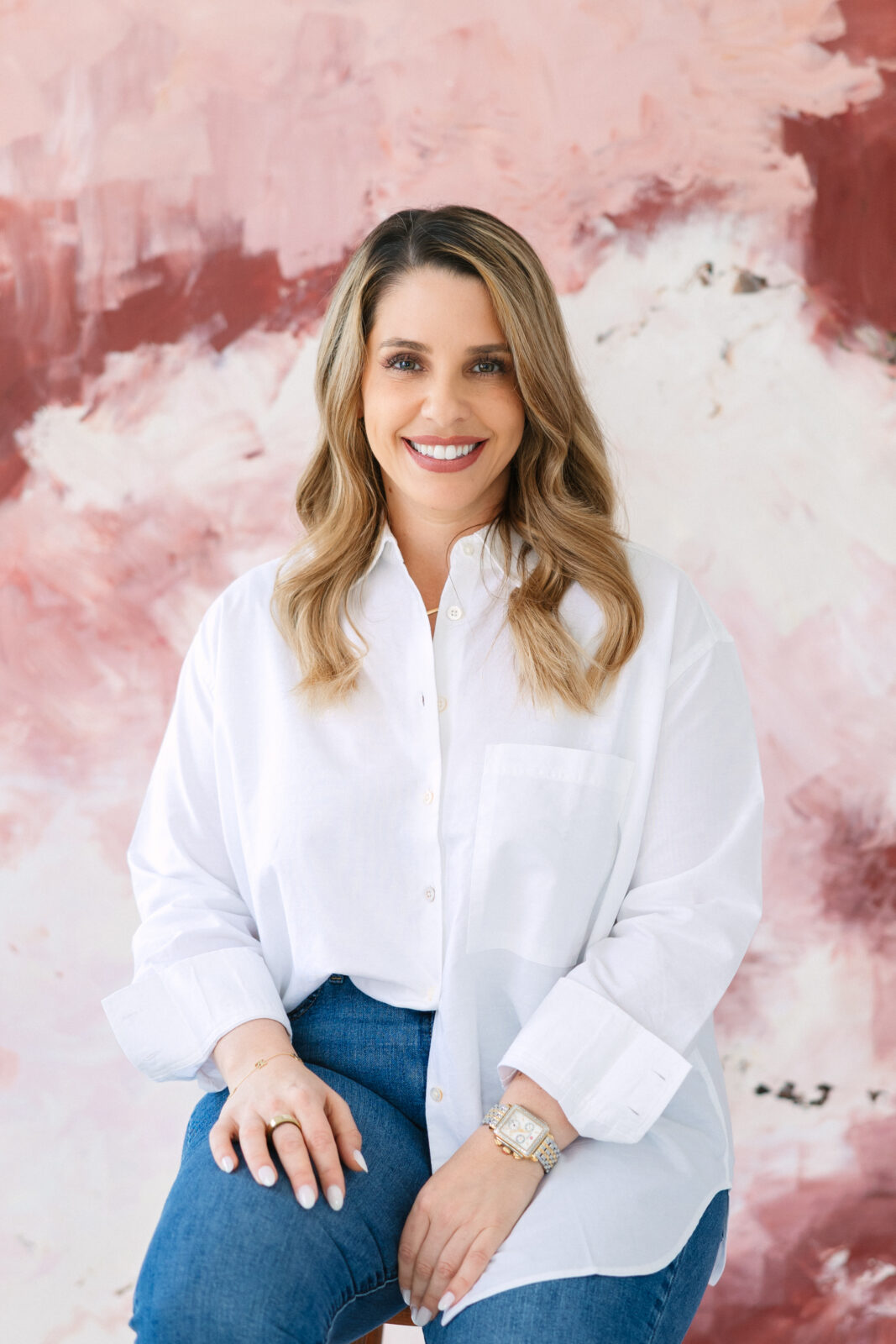 woman smiling, wearing a crisp white shirt with a pink and white canvas backdrop
