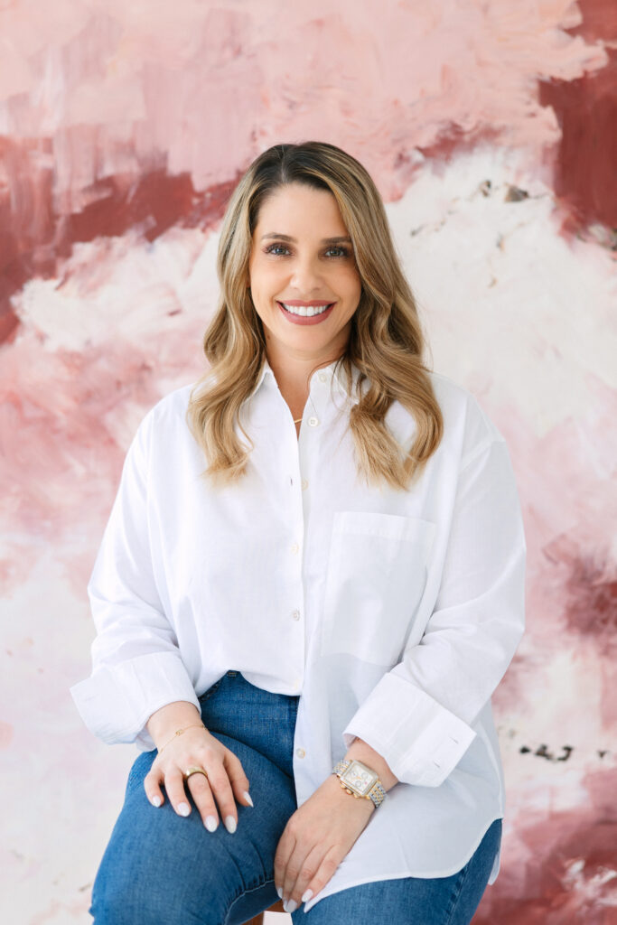 woman smiling, wearing a crisp white shirt with a pink and white canvas backdrop