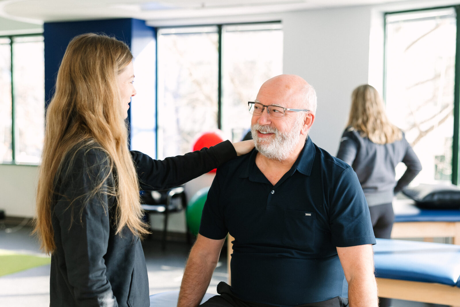 A physical therapist and her patient smiling at each other.