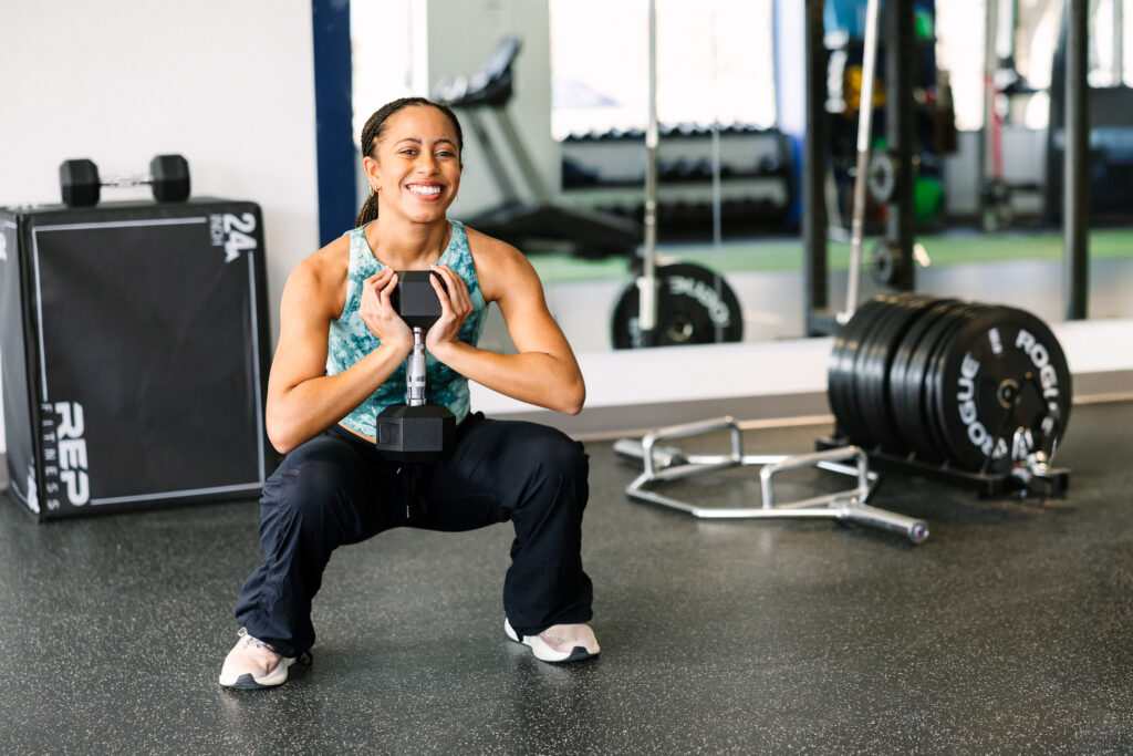 A woman in a deep goblet squat, holding a dumbbell