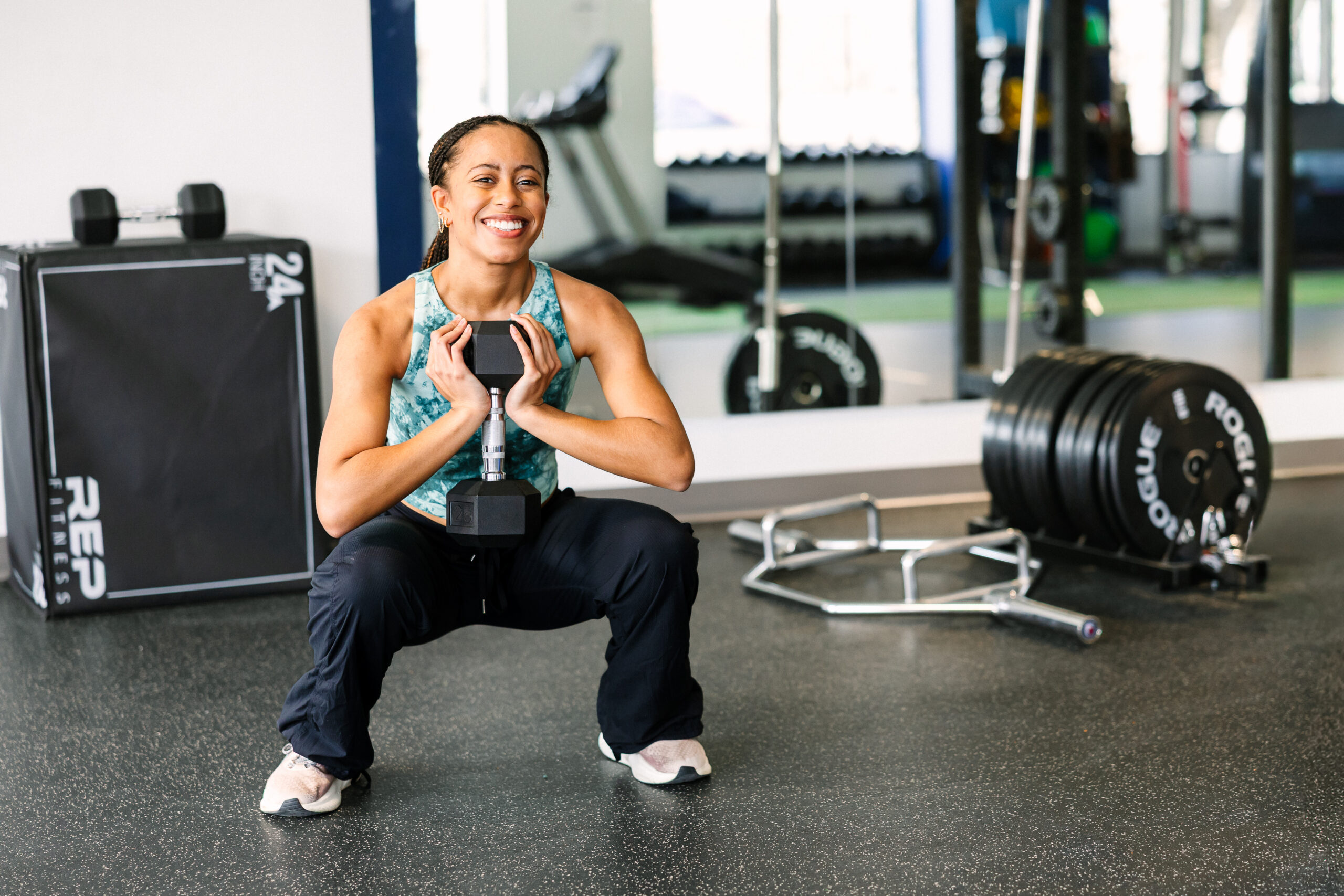 A woman in a deep goblet squat, holding a dumbbell