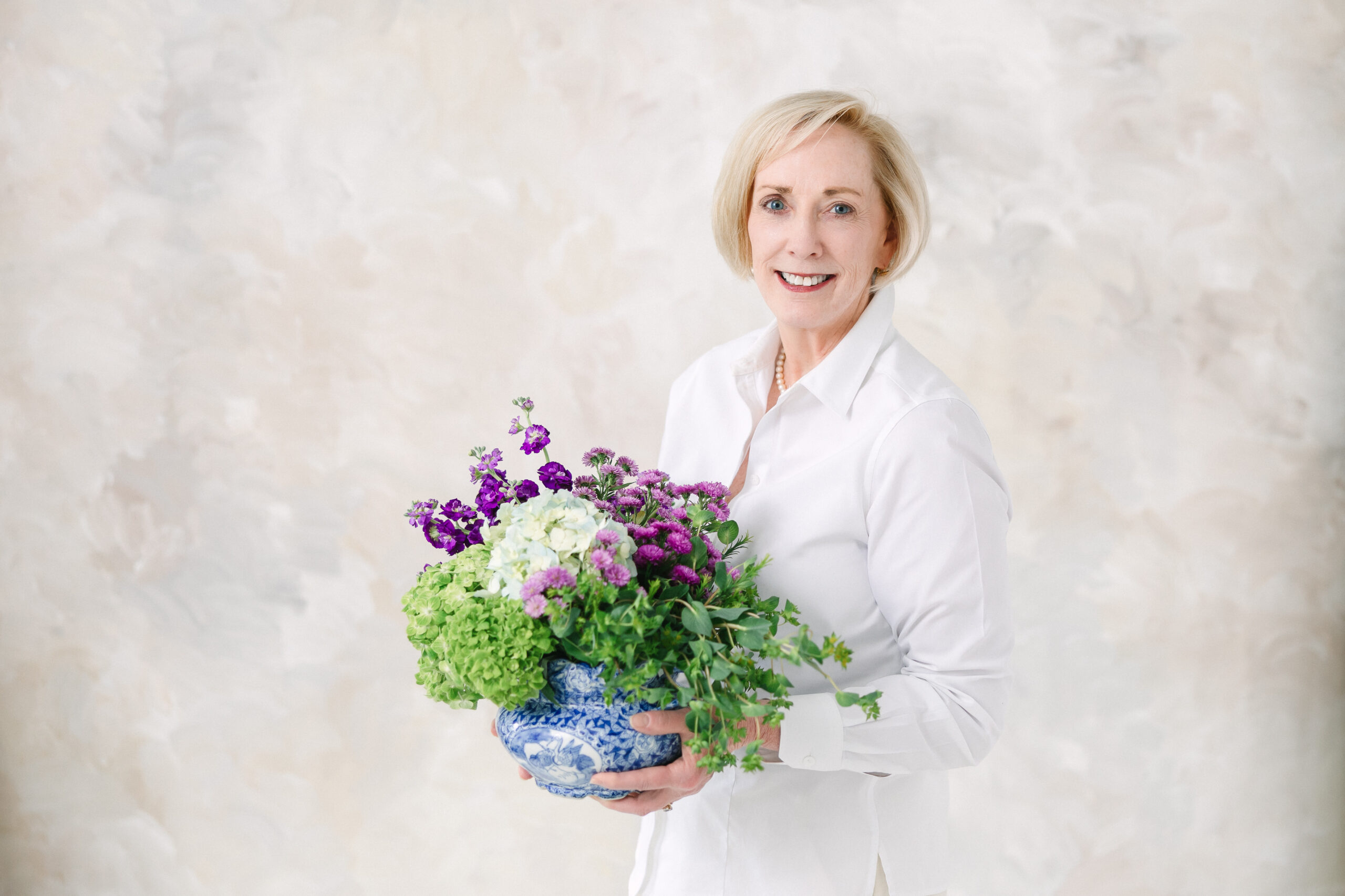 Using a flower arrangement in this professional headshot of the president of the Virginia Garden Board, helps tell a story and keep the image on brand.