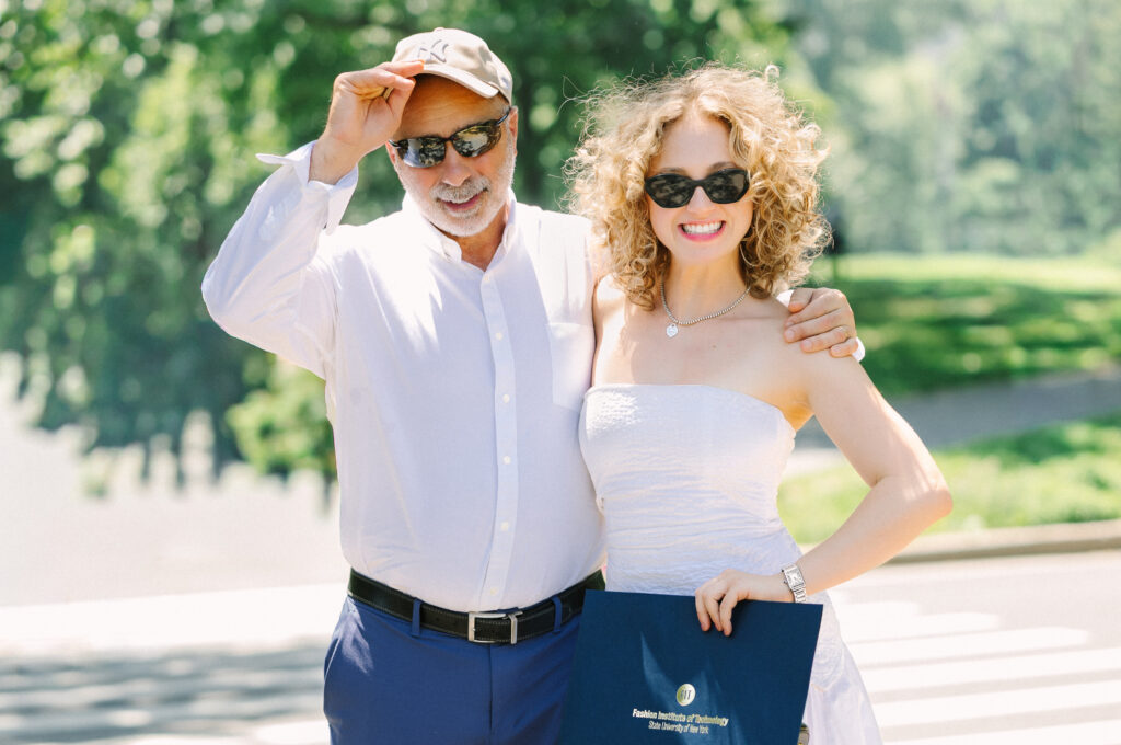a graduate with her father, holding her diploma from fit
