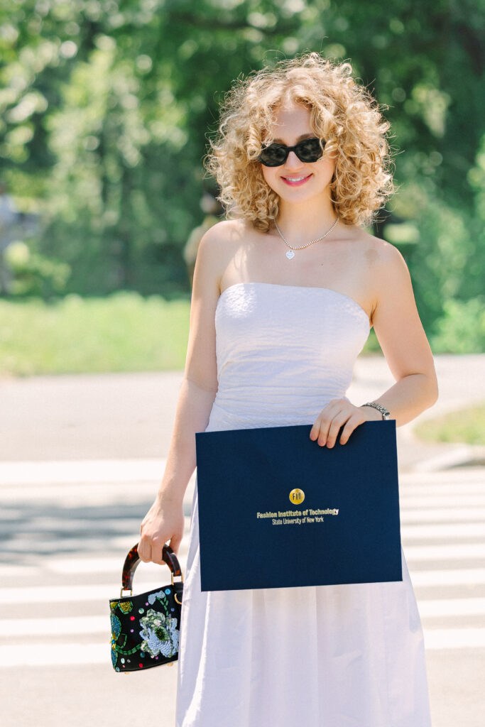 a graduate holding her college diploma from the fashion institute of technology