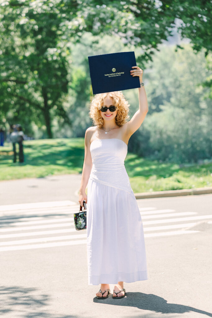 an fashion institute of technology graduate holding her diploma above her head