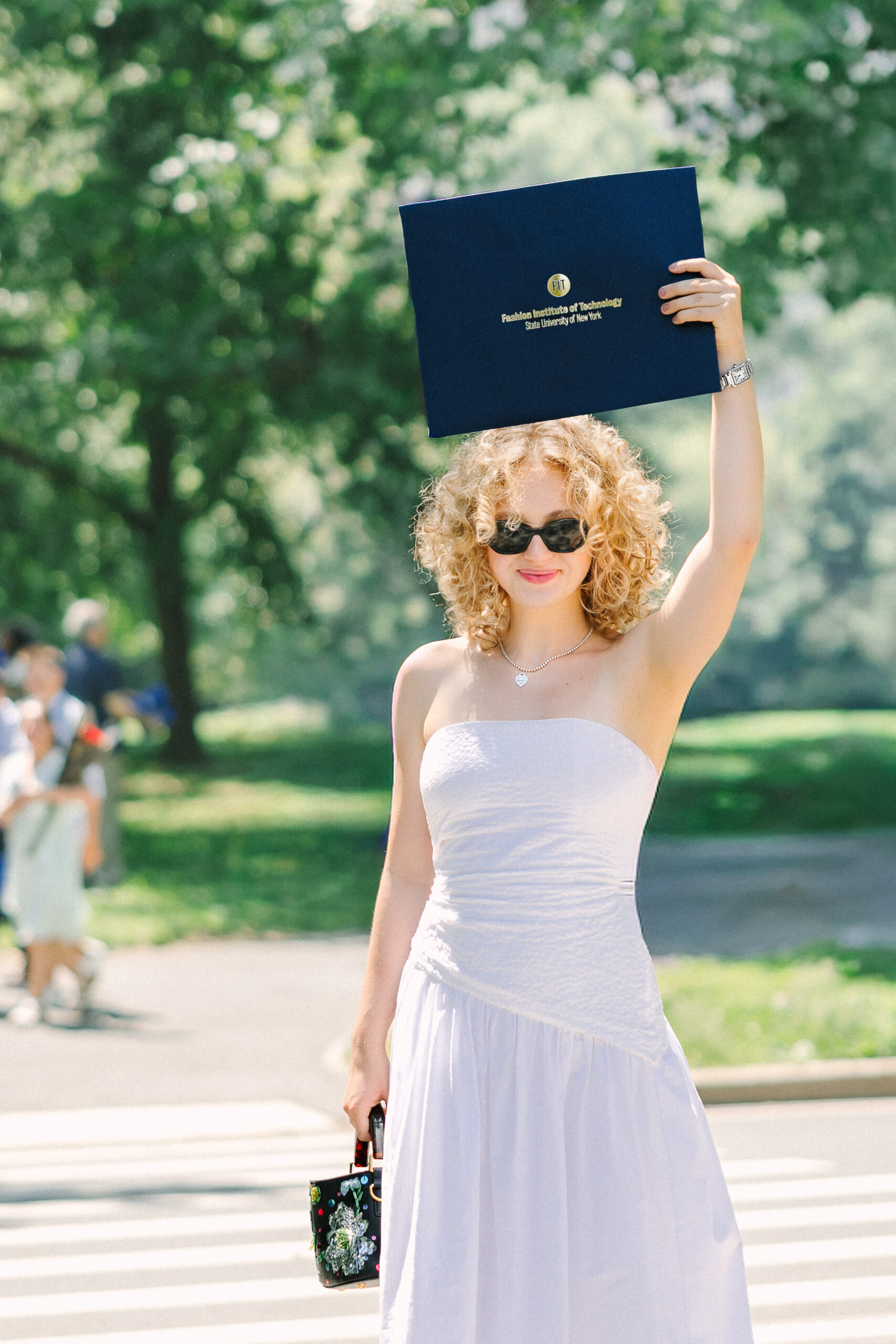 a graduate holding her diploma from fit above her head