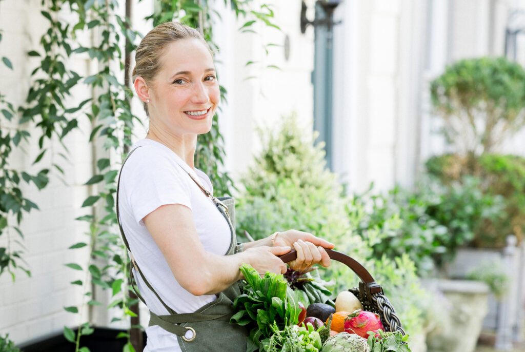 Holistic health coach holding a basket of fresh produce during a personal brand photography session outdoors.