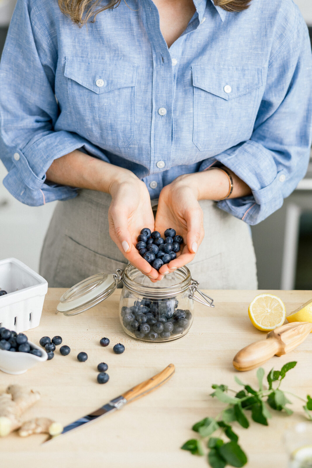 A wellness coach with blueberries in her hands, forming the shape of a love heart.
