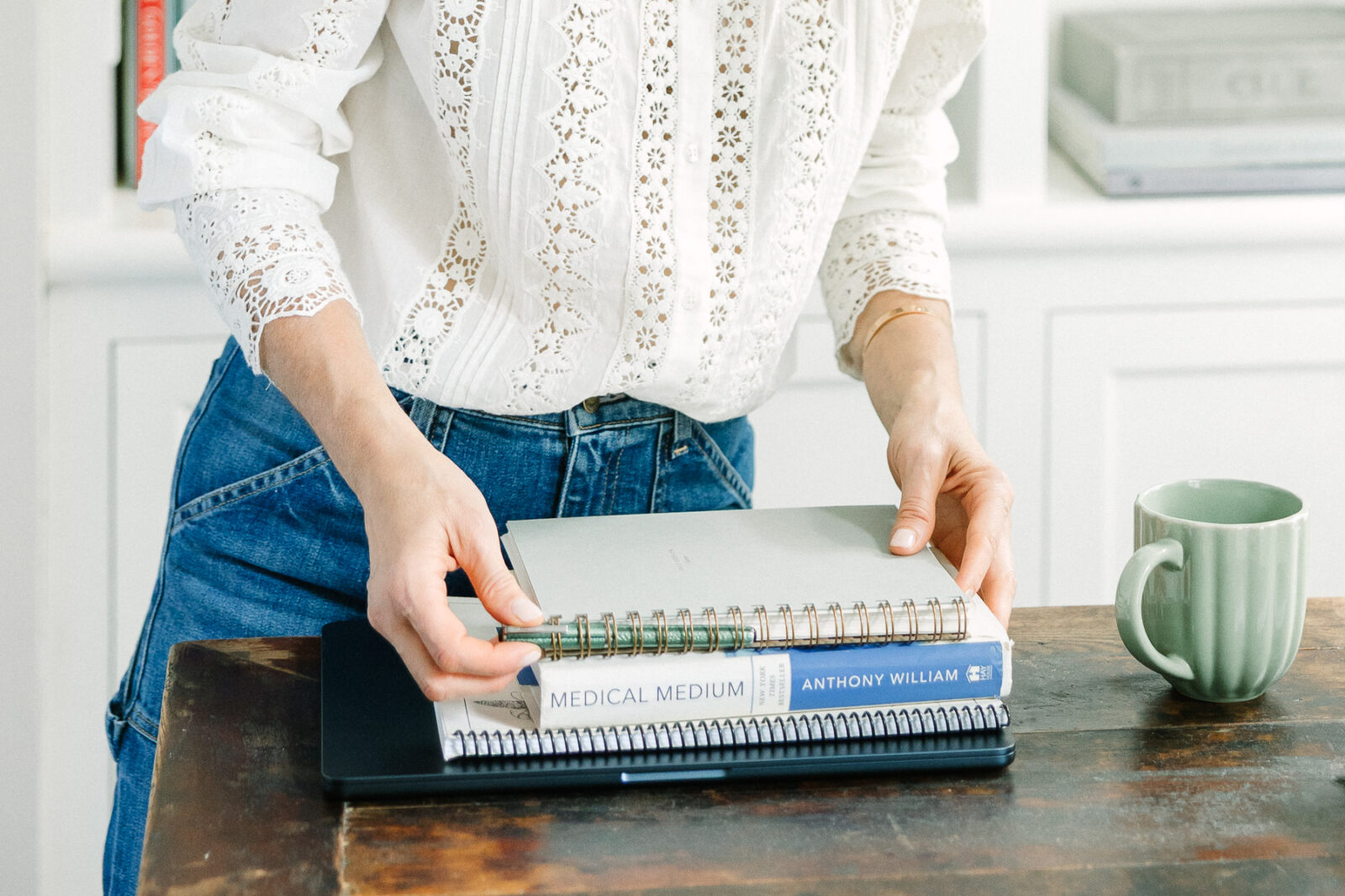 Wellness coach organizing her text and notebooks on a wooded desk.