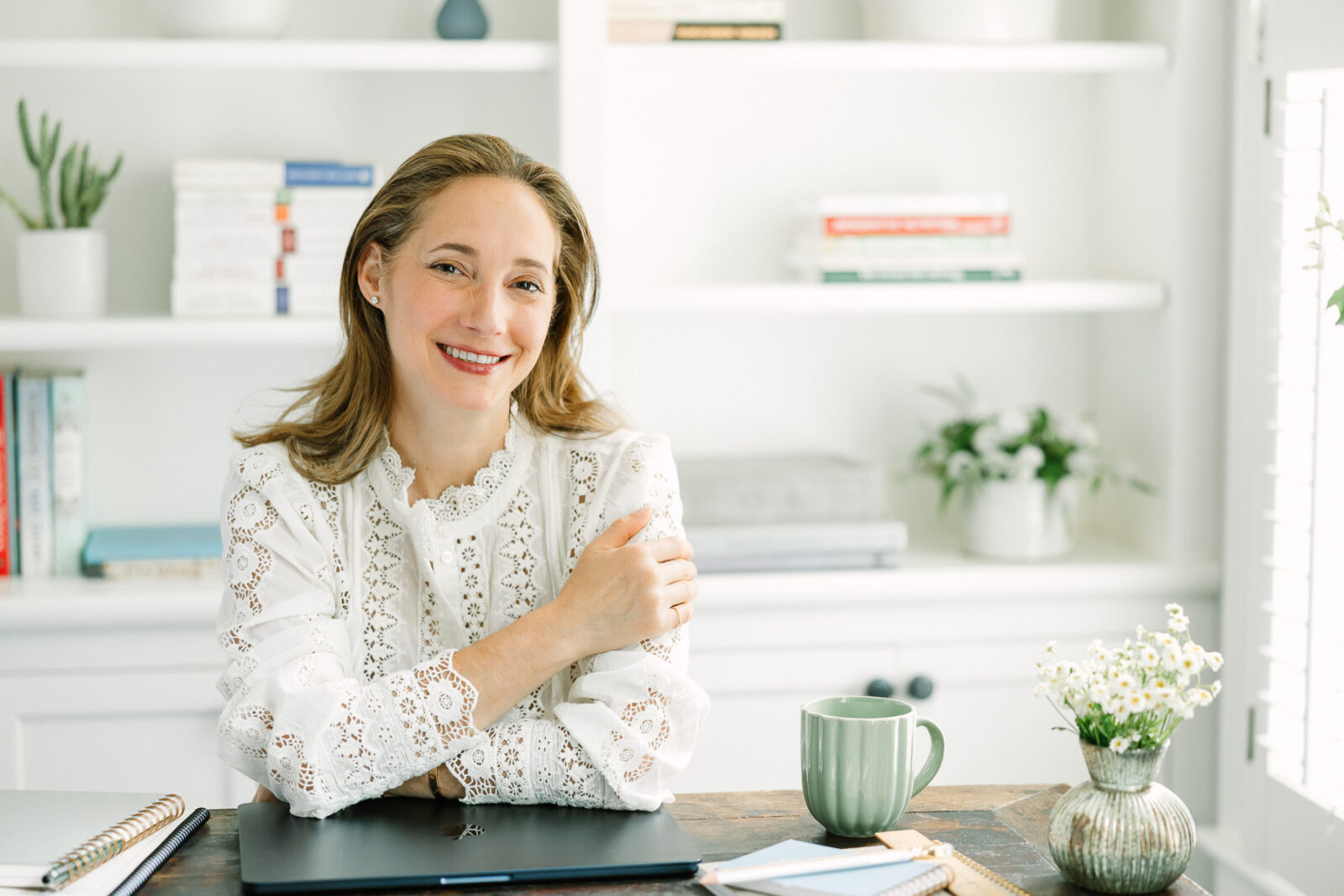 Wellness coach sat at a desk, with a laptop and notebooks.